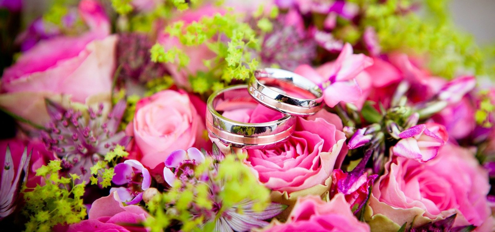 Hochzeit 2, © pixabay Zwei silberne Eheringe liegen auf einem Brautstrauß aus pinken Rosen