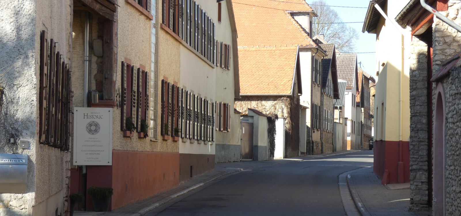 Hauptstraße im idyllischen Weindorf Dexheim, © TSC Rhein-Selz Enge Straße mit alten Häusern und Holzläden in einem ruhigen Dorf