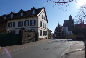 Stra&szlig;e mit altem Haus links und Kirche im Hintergrund bei sonnigem Himmel