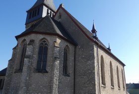 Steinerne Kirche mit spitzem Turm und gotischen Fenstern bei klarem Himmel