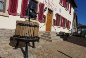 Eingang mit Treppen zum Rathausgeb&auml;ude, davor eine historische Weinpresse
