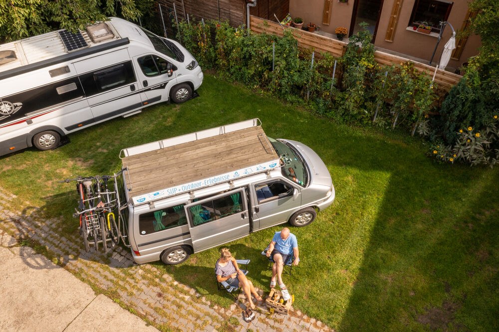 Luftaufnahme eines Reisemobilstellplatzes im Innenhof mit Garten eines Weinguts
