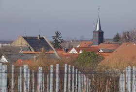 Blick von umliegenden Weinbergen auf ein Weindorf mit Kirche im Zentrum