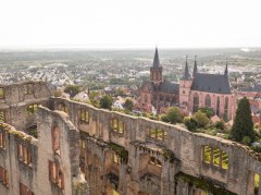 Luftaufnahme von einer Burgruine, eine Kirche und Stadt im Hintergrund