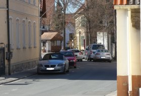 Eine ruhige Stra&szlig;e mit geparkten Autos, umgeben von alten Geb&auml;uden