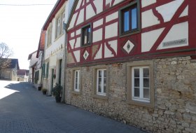 Fachwerkhaus mit rotem Holzrahmen und wei&szlig;em Mauerwerk an einer ruhigen Stra&szlig;e mit Pflastersteinen
