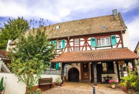 Fachwerkhaus mit gr&uuml;nen Fensterl&auml;den, rotem Ziegeldach und &uuml;berdachtem Eingang