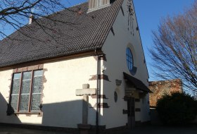 Kleine wei&szlig;e Kirche mit steilem Dach und kleinem Holzturm vor blauem Himmel