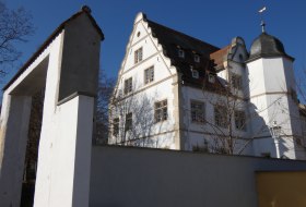 Historisches wei&szlig;es Geb&auml;ude mit Turm hinter einer Mauer