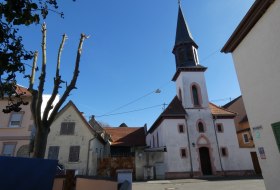 Kirche mit spitzem Turm und wei&szlig;er Fassade in einem kleinen Dorf