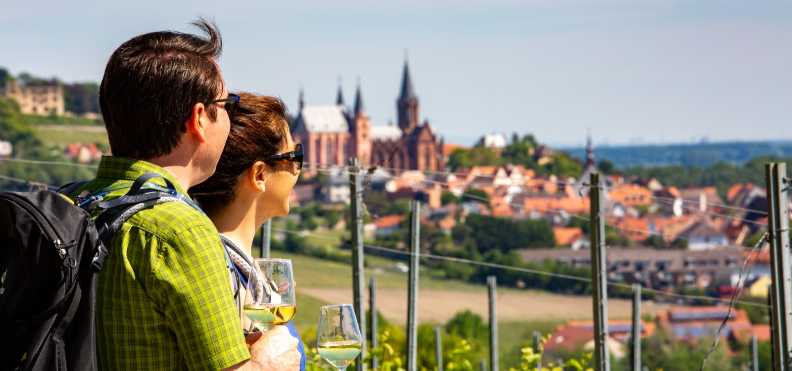 Ein Paar blickt bei einer Wanderung auf Weinberge und eine Stadt mit Kirche