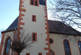 Kirchturm mit spitzem Dach und Wetterfahne, an einem klaren Tag 